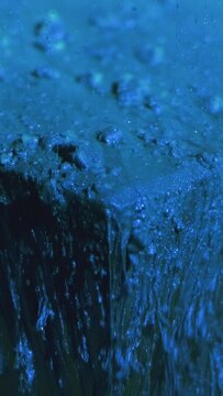 Vertical video. Paint drip. Glitter fluid. Ice cascade. Blue color sparkling flakes texture ink fall motion on cube angle abstract background.
