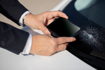 Business person taking a photo of the VIN number on the car behind the cracked windshield for an insurance company 