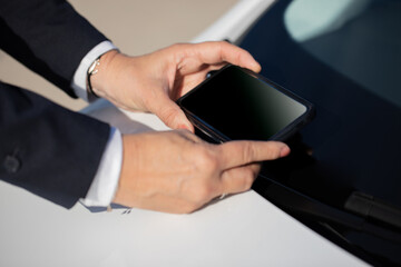 An elderly person taking a photo of the VIN number on the car behind the windshield for an insurance company