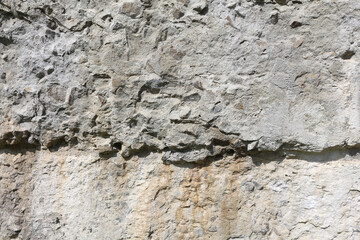 Grunge background texture. An old weathered wall. Plastered stone surface with rocks.