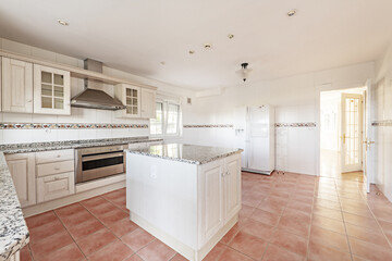 Large kitchen room with old-fashioned white cabinets with polished granite countertops and matching island