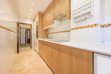 Long kitchen furnished with cherry cabinets, white countertops and white built-in appliances