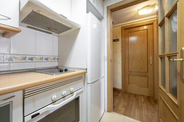 Fototapeta premium Small kitchen with white appliances and oak access door with beveled glass