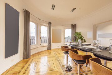 Semicircular living room with varnished hardwood floors with a high gray board table and wooden and chrome metal stools