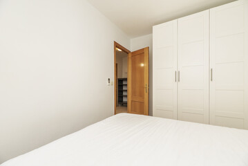 Bedroom with a wardrobe with four white wooden doors and oak doors with a brass handle