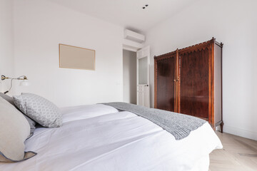 Bedroom with vintage-style mahogany wardrobe and double bed with white feather duvet