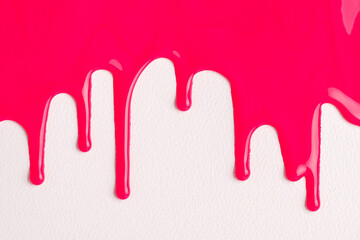 Pink liquid drops of paint color flow down on white canvas. Abstract art. Red paint dripping on the...