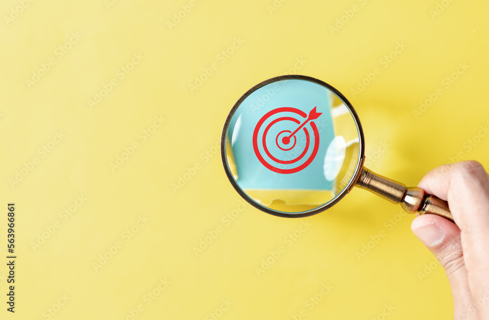 Aufkleber dartboard with arrow hiding of yellow punched paper, hand holding magnifying discovery target for pl
