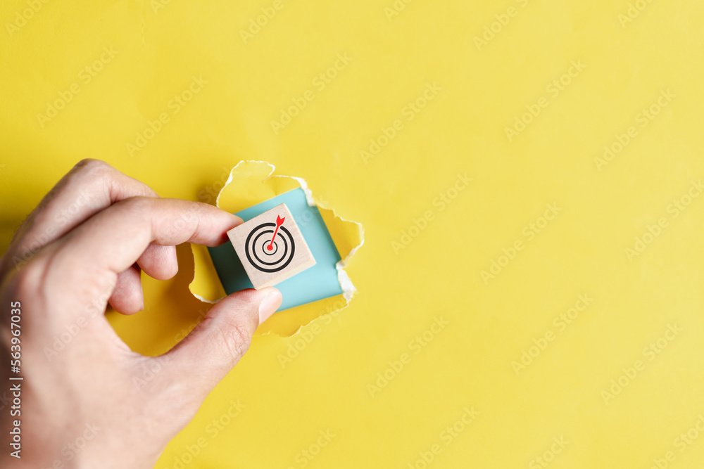 Fototapete Dartboard with arrow hiding of yellow punched paper, hand picking cube block with dart icon target for planning business objective target to successful development, innovation, idea, creative.