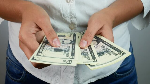 Counting five dollar bills in his hands. A woman in a white shirt counts money.