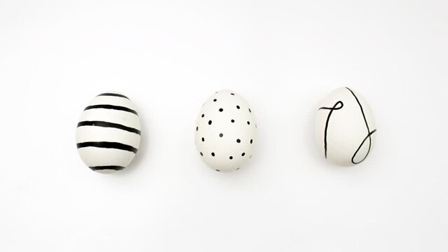 Animated video from above. Top view. Drawing of egg appears on white background. Chicken eggs with black dots, stripes, linear pattern. 4K Happy Easter greeting card. Preparation for celebration. Food
