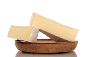 Two pieces of fragrant Brie cheese on a wooden plate, macro, isolated on white background.