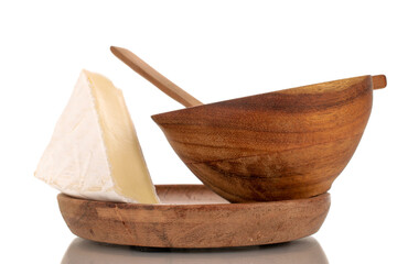 One piece of fragrant Brie cheese on a wooden saucer with a wooden cup, macro, isolated on white background.