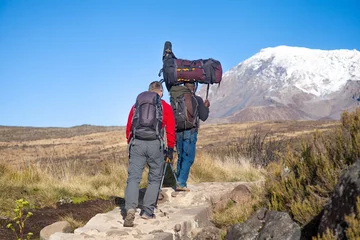 Photo sur Plexiglas Kilimandjaro A porter carrying heavy load on his head on the way to Kilimanjaro mountain. Tanzania.