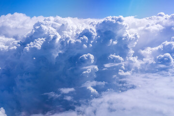 White cloud on blue sky. See through the plane window in sunny weather bird's eye view.