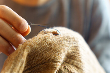 Mending clothes. Old worn woolen clothes. Repair concept, selective focus - obrazy, fototapety, plakaty