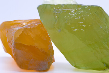 Macro focused raw shiny semi-transparent vibrant orange and pistachio lime green calcite mineral, calcite stone, two bright carbonate crystals isolated on a white surface background