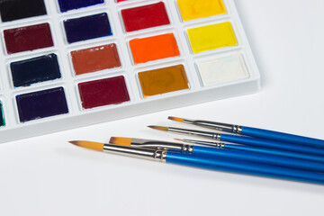 Paint brushes on a set of watercolor paints on a white background. drawing tools.