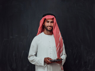 Young arabian muslim businessman using tablet computer wearing hijab clothes in front of black...
