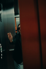 Fototapeta na wymiar Stylish woman in black jacket and sunglasses posing in elevator, fashion model, dark cinematic light and color, glamor vintage