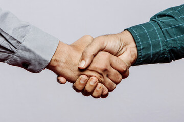 Business Partners shaking hands together greeting start up small business in grey studio background.
