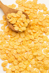 Copos de maíz junto a una cuchara de madera de bambú. Vista superior y de cerca. Formato vertical