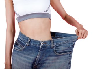 Woman shows weight loss. Slim woman is happy to show her big old jeans. Fit woman in oversize blue jeans on pastel pink background. Diet and weight loss concept.