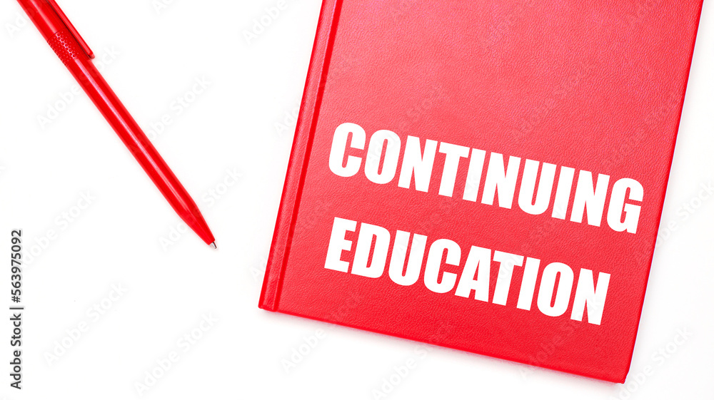 Poster the text continuing education is written on a red notepad near a red pen on a white table in the off