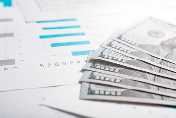 Business and finance concept. Close-up of money lying on documents on desktop. Low angle view, selective focus on dollars