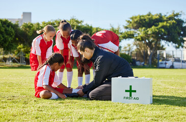 Sports, first aid and children soccer team with an injury after a game in a huddle helping a girl athlete. Fitness, training and kid with a sore, pain or muscle sprain on an outdoor football field. - obrazy, fototapety, plakaty