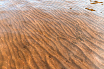 Seabed with wavy pattern on sand under shallow water