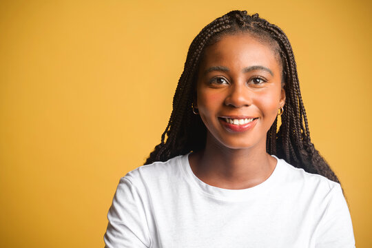 Close-up portrait of attractive young brunette woman, female with natural beauty looks at the camera and laughs, isolated on yellow background