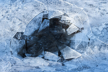 Hole in thin ice on a frozen lake, abstract winter background