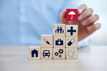 Insurance, wood building blocks and sign with hand for home, healthcare and car on desk for...