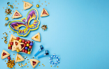 Purim Hamantaschen Cookies, Carnival Mask, Noisemaker, Sweet Candies on Blue Background.