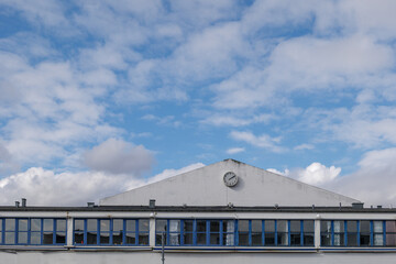 Outdoor exterior view at the detail of gable roof of mix-use industrial building against blue sky. 