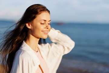 Woman portrait smile with teeth freedom vacation walking on the beach by the ocean in Bali sunset, happy journey and relaxation, sunset light, flying hair, the concept of change and emotional health