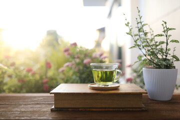 Green Tea in a glass cup and kraft paper notebook with flower background