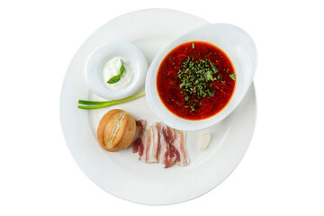 Borscht with sour cream, lard, bread and green onions in a white plate. Appetizing traditional dish of Russian and Ukrainian cuisines. Top view. Close-up. Isolated on white background.