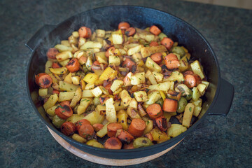 ready to eat - grilled sliced potatoes, yellow paprika, olives, red onions, debreziner and herbs in a hot pan