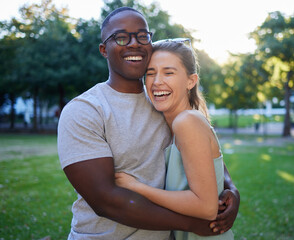 Love, interracial or couple of friends hug in a park on a happy romantic date bonding in nature together. Romance, funny black man and woman laughing or enjoying quality time on a holiday vacation