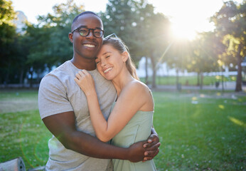 Love, hug or couple of friends in a park on a relaxing romantic date in nature in an interracial relationship. Bonding, black man and happy woman enjoying quality time on a holiday vacation together