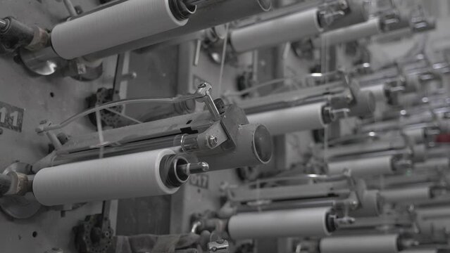 This stock video shows the winding of threads on bobbins in a weaving factory. This video will decorate your projects related to weaving, fabric production, textile industry.
