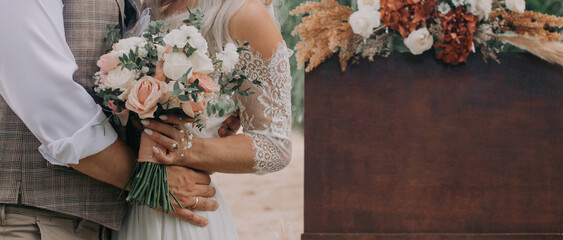 Newly wife and husband with beautiful bouquet standing next to a welcome board sign with flower rustic decoration