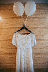 Beautiful white wedding dress hangs on a hanger indoors. Close-up photo, bride morning.