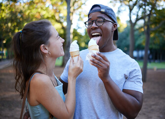 Naklejka premium Interracial, ice cream or couple of friends in a park walking on a fun romantic date in nature bonding together. Romance, relaxed black man and happy woman loves eating a snack on a holiday vacation