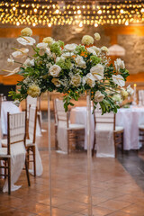 Wedding banquet or gala dinner decorated with garlands. Round tables styled with flowers, candles...