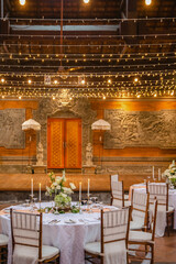 Wedding banquet or gala dinner decorated with garlands. Round tables styled with flowers, candles and accessories. Festive banquet during dusk