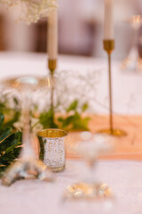 Beautiful table setting decorated with lighted candles, tableware, flowers, accessories for a party, wedding reception, gala banquet or other holiday event.
