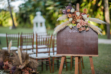 A welcome board sign with a beautiful flower and rustic decoration, standing in front of wedding...